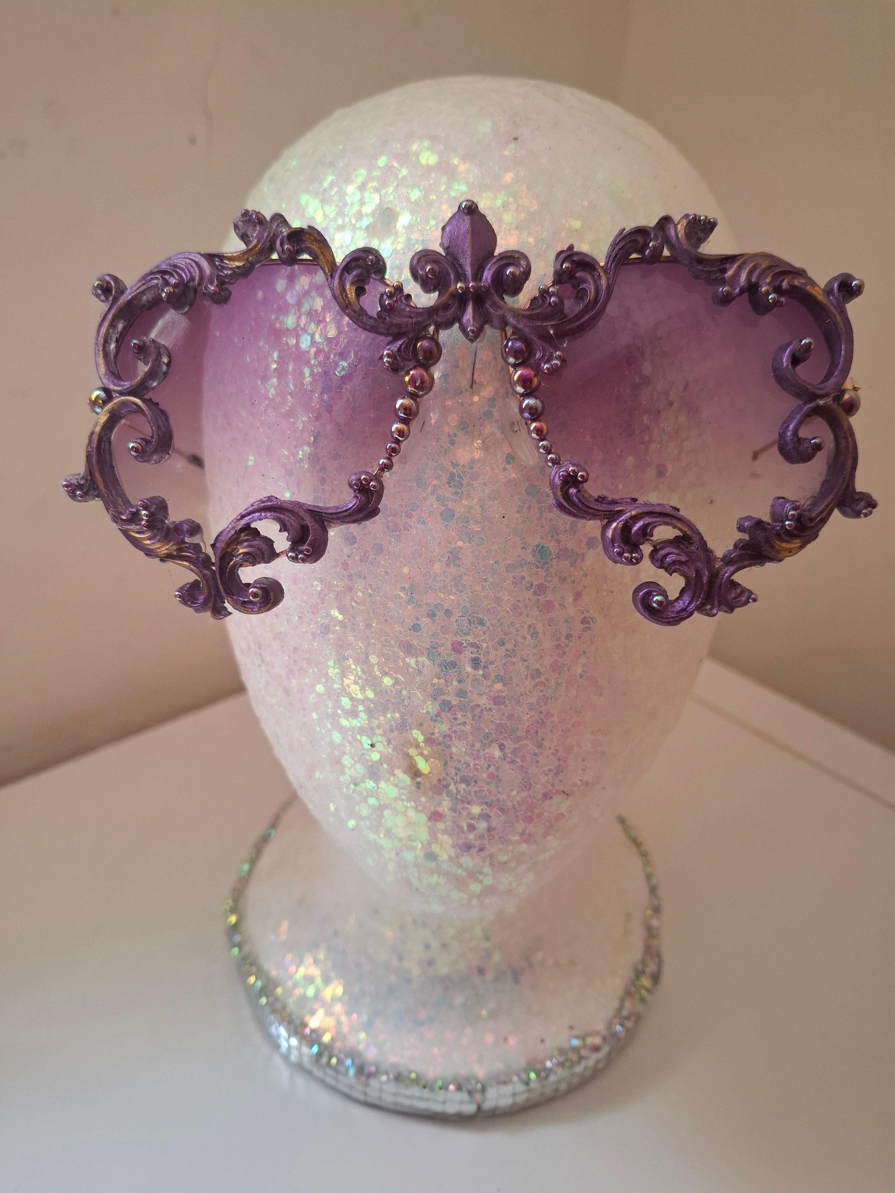 Hand-sculpted sunglasses in deep purple scrollwork with gold foil accents and a fleur-de-lis crown