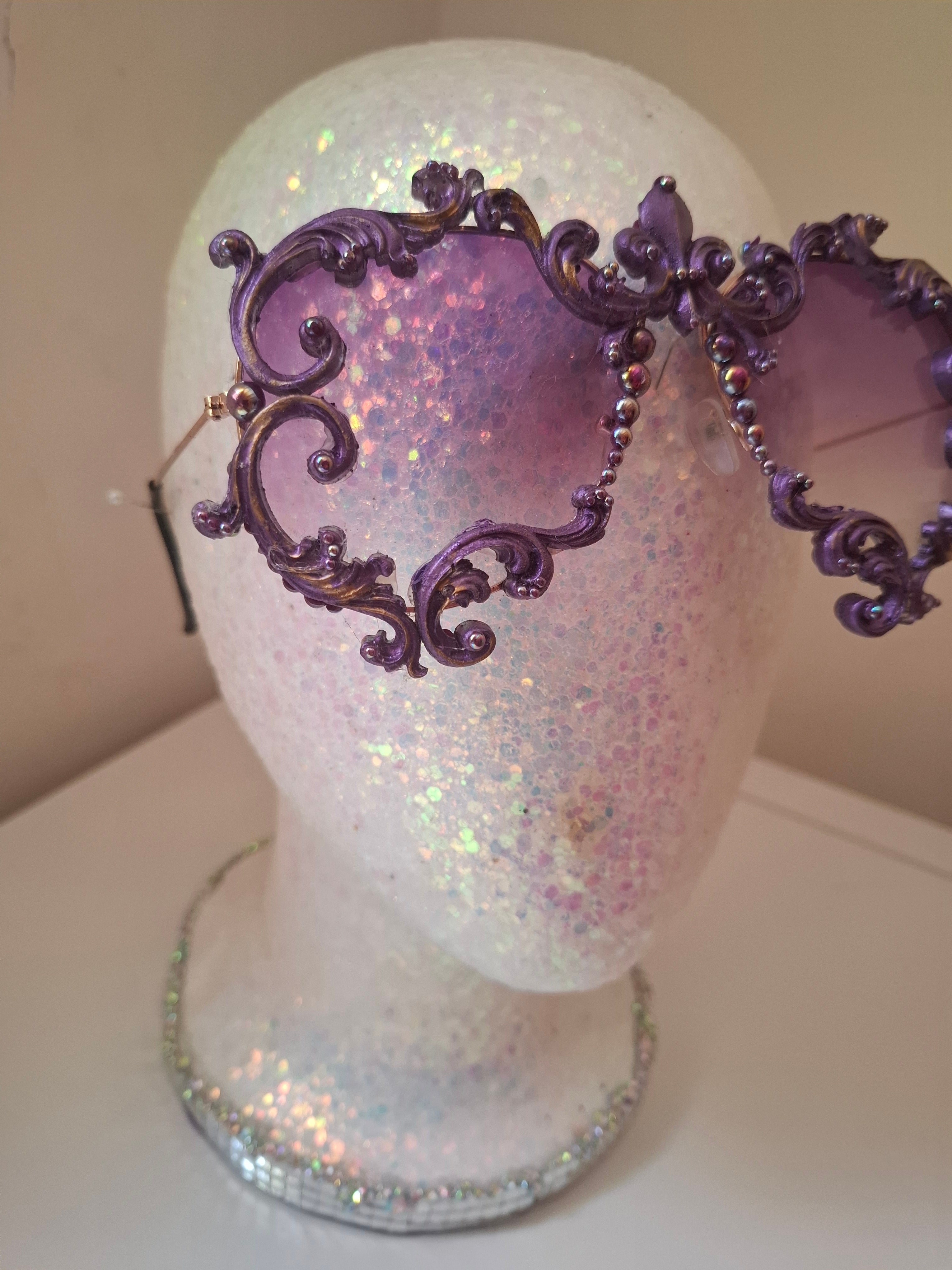 Hand-sculpted sunglasses in deep purple scrollwork with gold foil accents and a fleur-de-lis crown