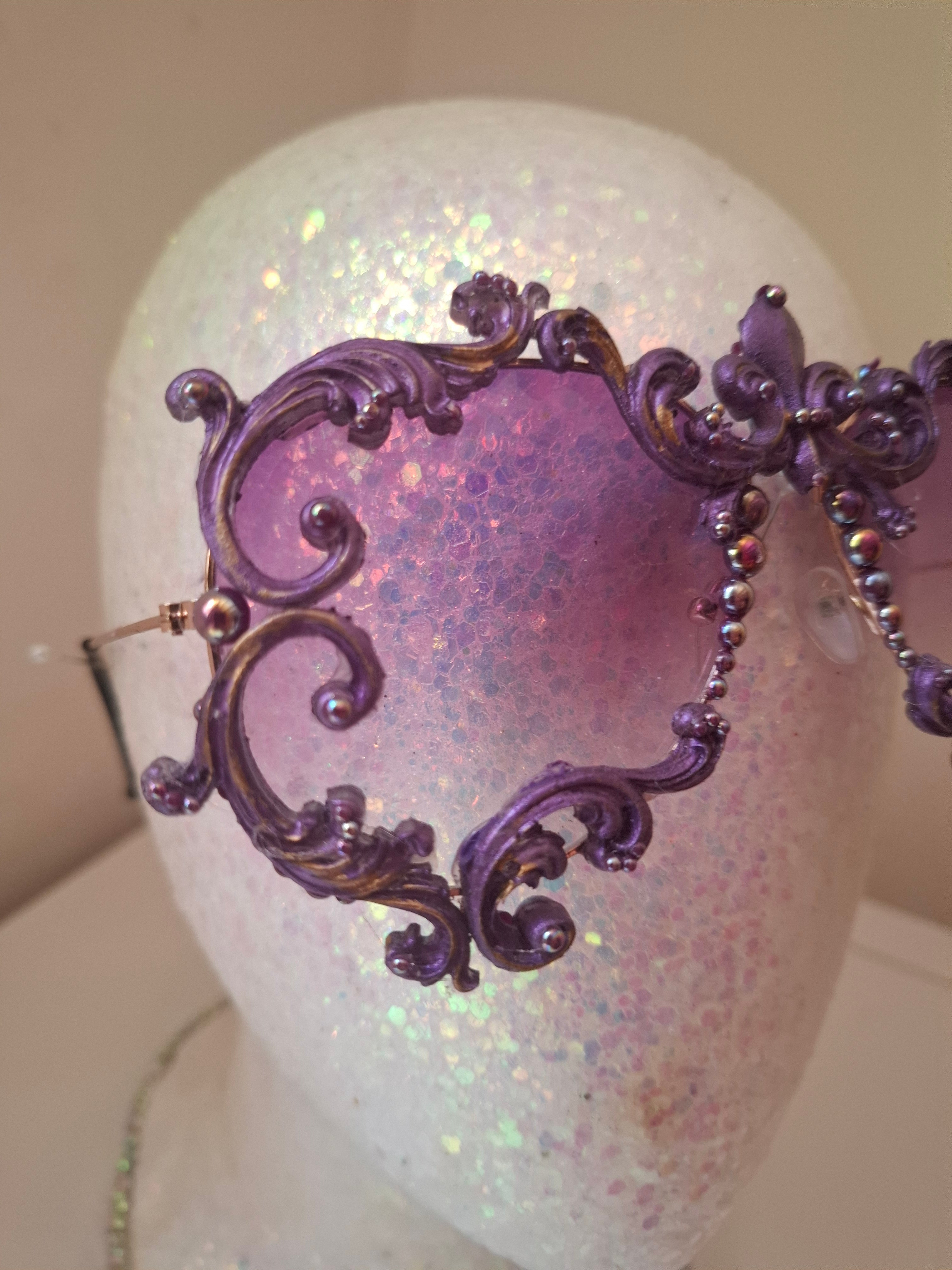 Hand-sculpted sunglasses in deep purple scrollwork with gold foil accents and a fleur-de-lis crown