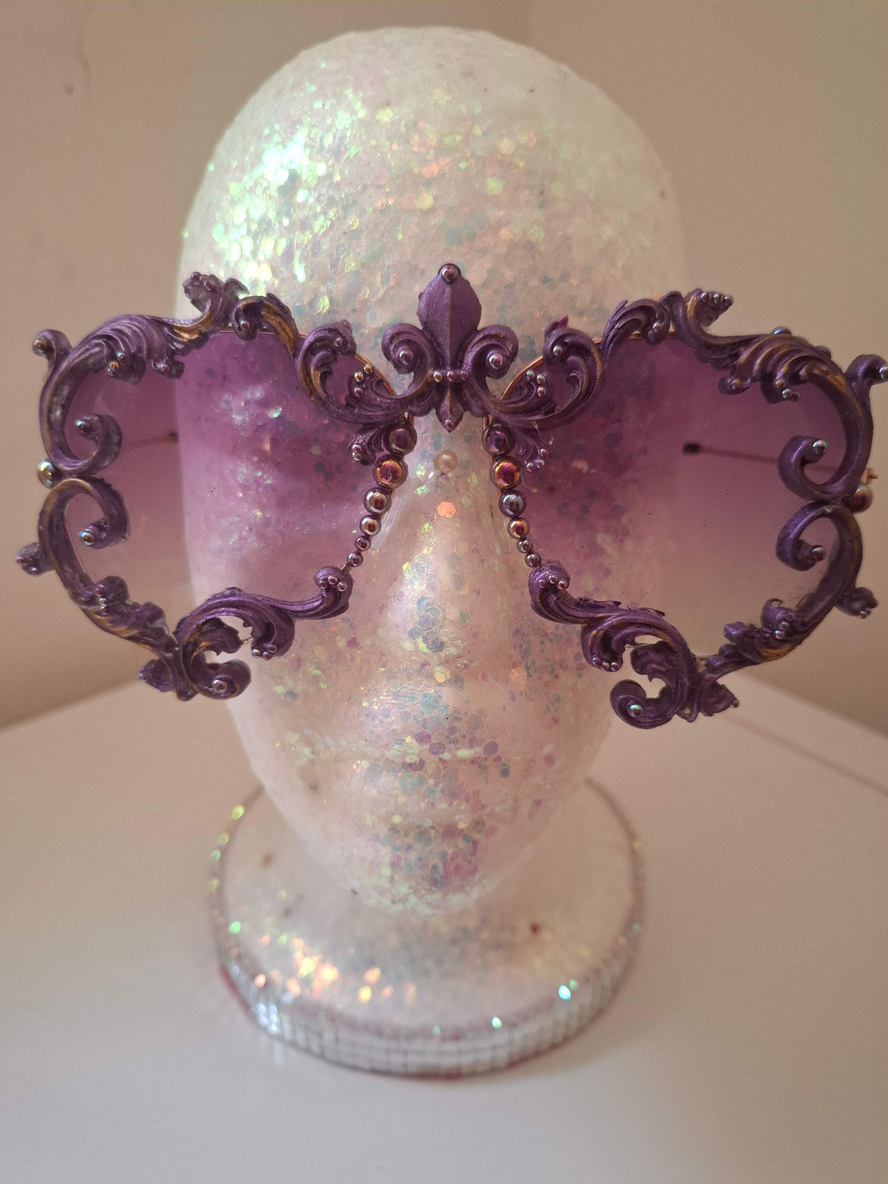 Hand-sculpted sunglasses in deep purple scrollwork with gold foil accents and a fleur-de-lis crown