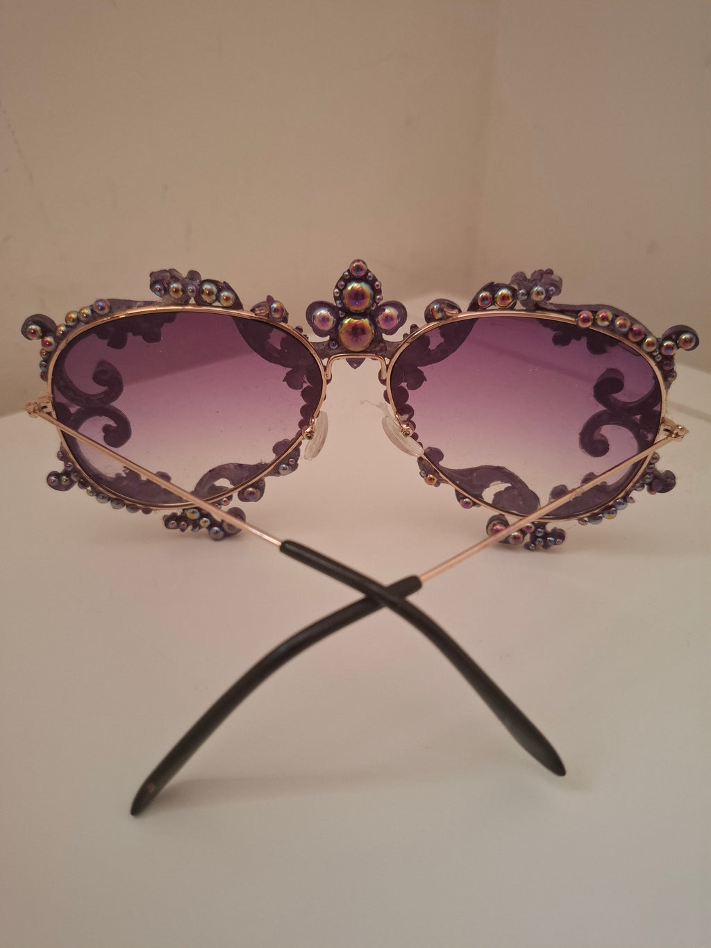 Hand-sculpted sunglasses in deep purple scrollwork with gold foil accents and a fleur-de-lis crown