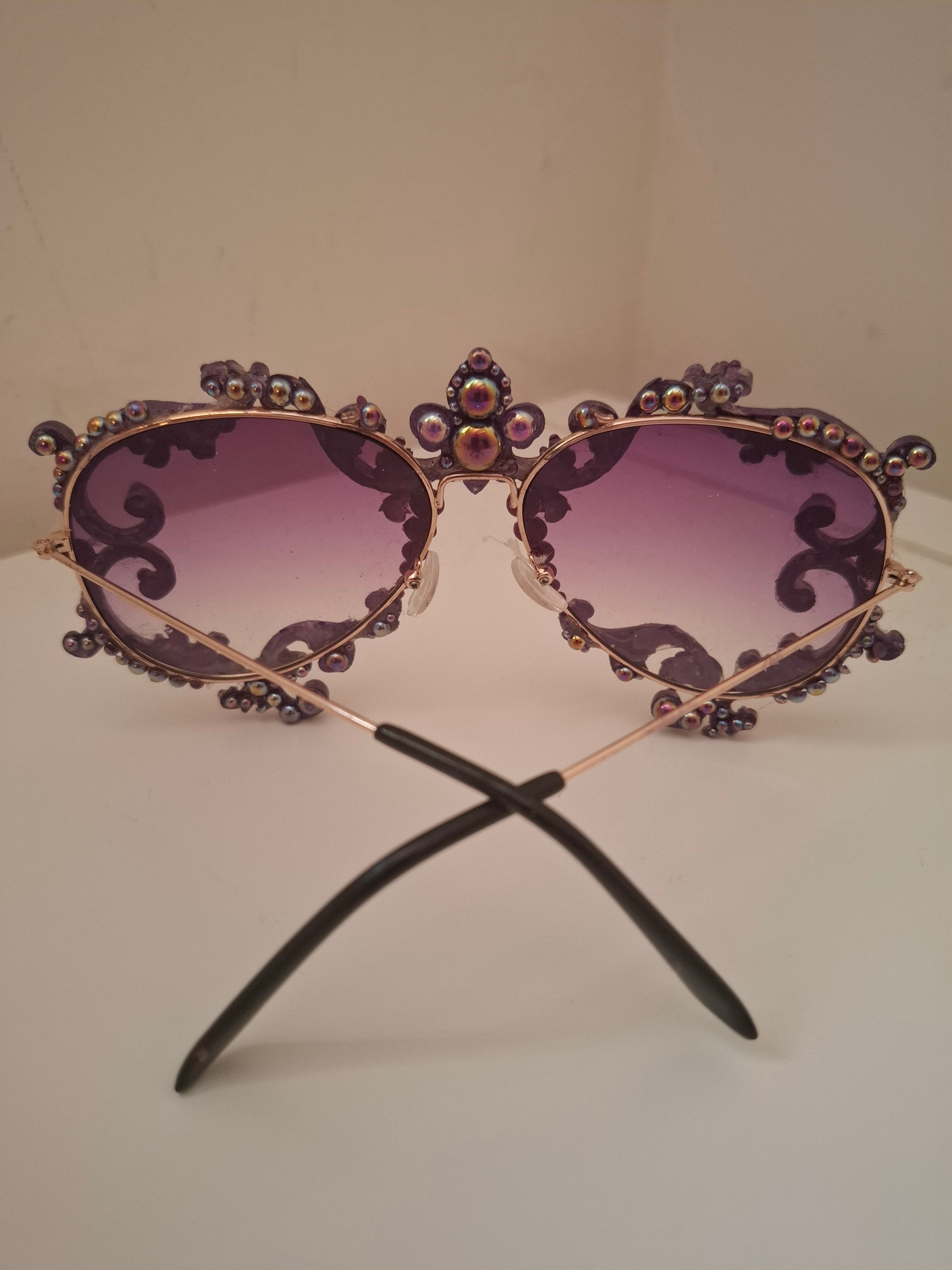 Hand-sculpted sunglasses in deep purple scrollwork with gold foil accents and a fleur-de-lis crown