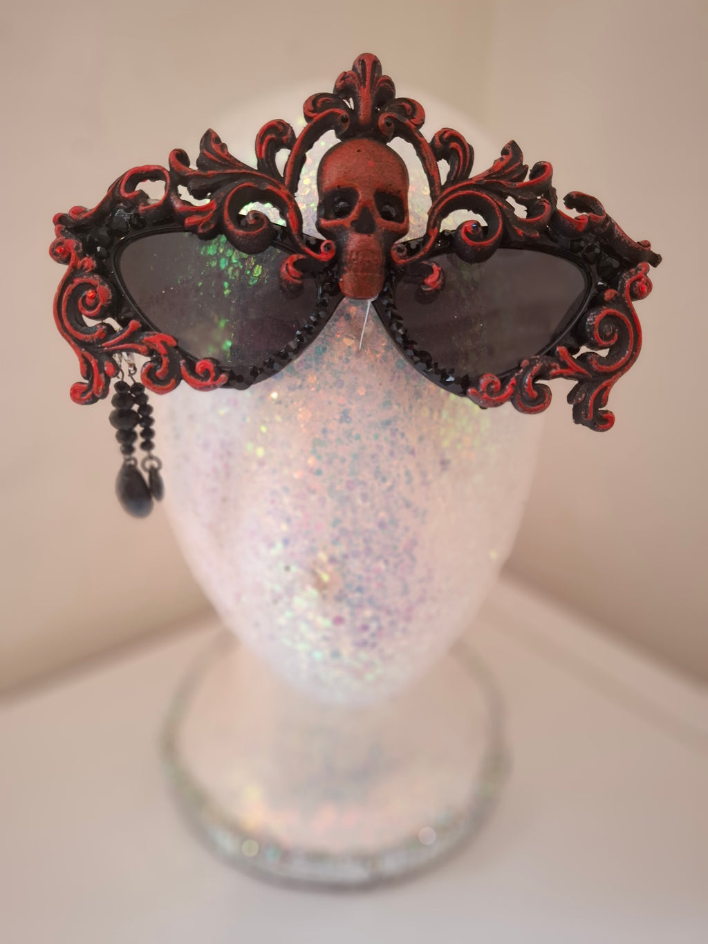 Hand-sculpted sunglasses in deep burgundy scrollwork with a skull centerpiece and black crystals