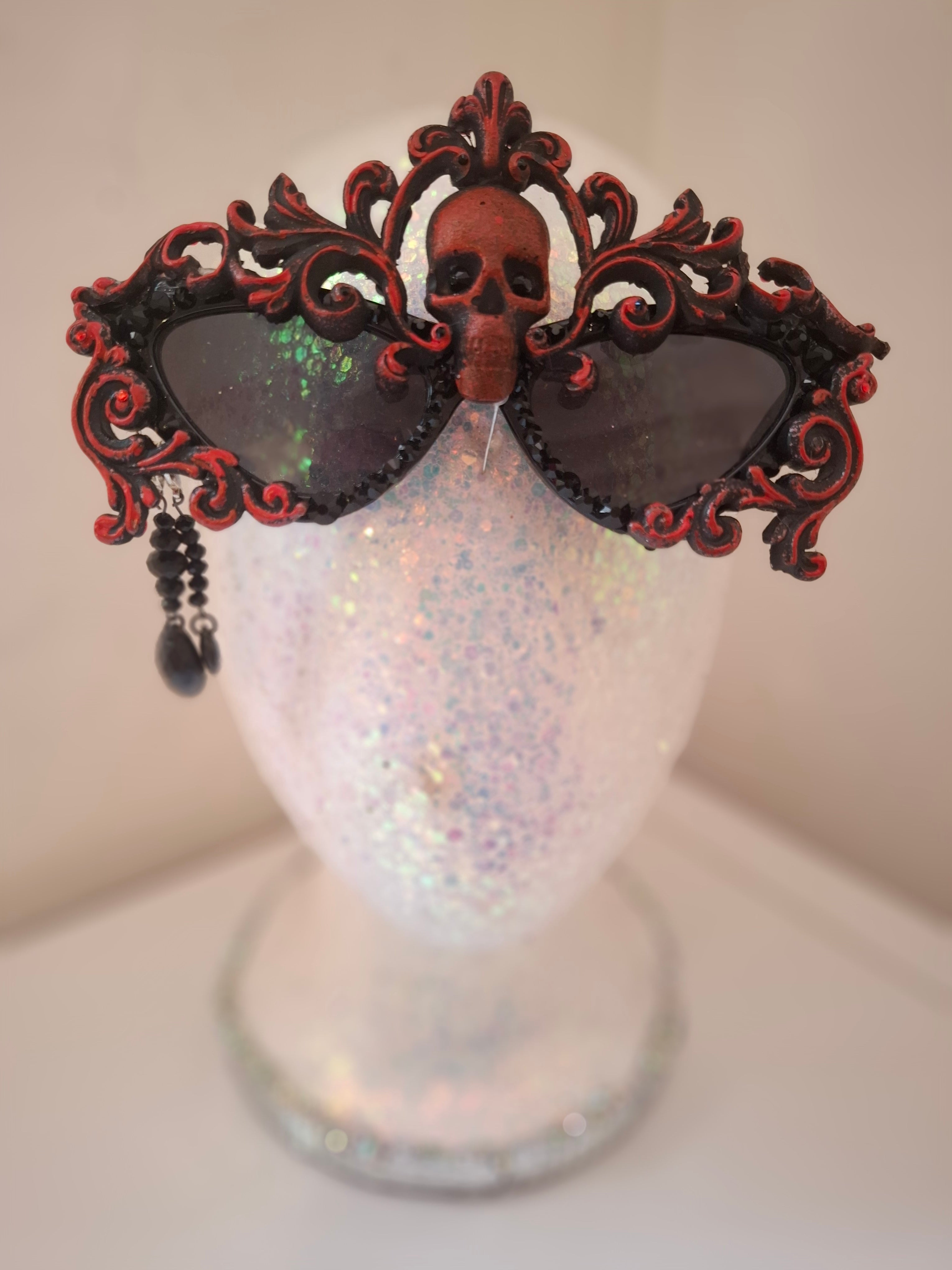 Hand-sculpted sunglasses in deep burgundy scrollwork with a skull centerpiece and black crystals