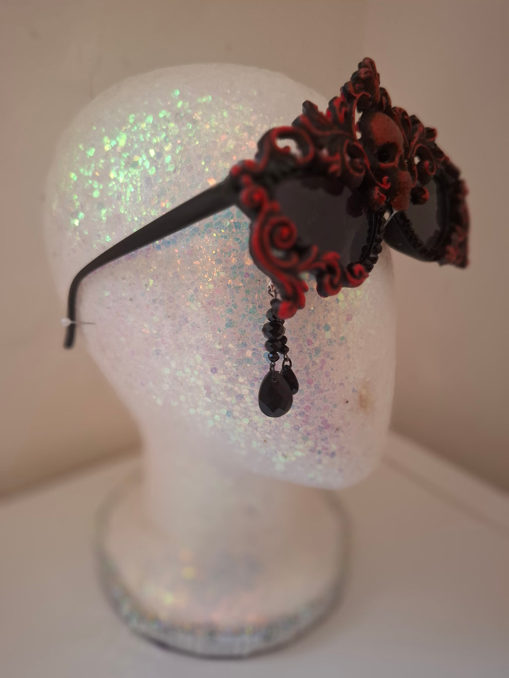 Hand-sculpted sunglasses in deep burgundy scrollwork with a skull centerpiece and black crystals