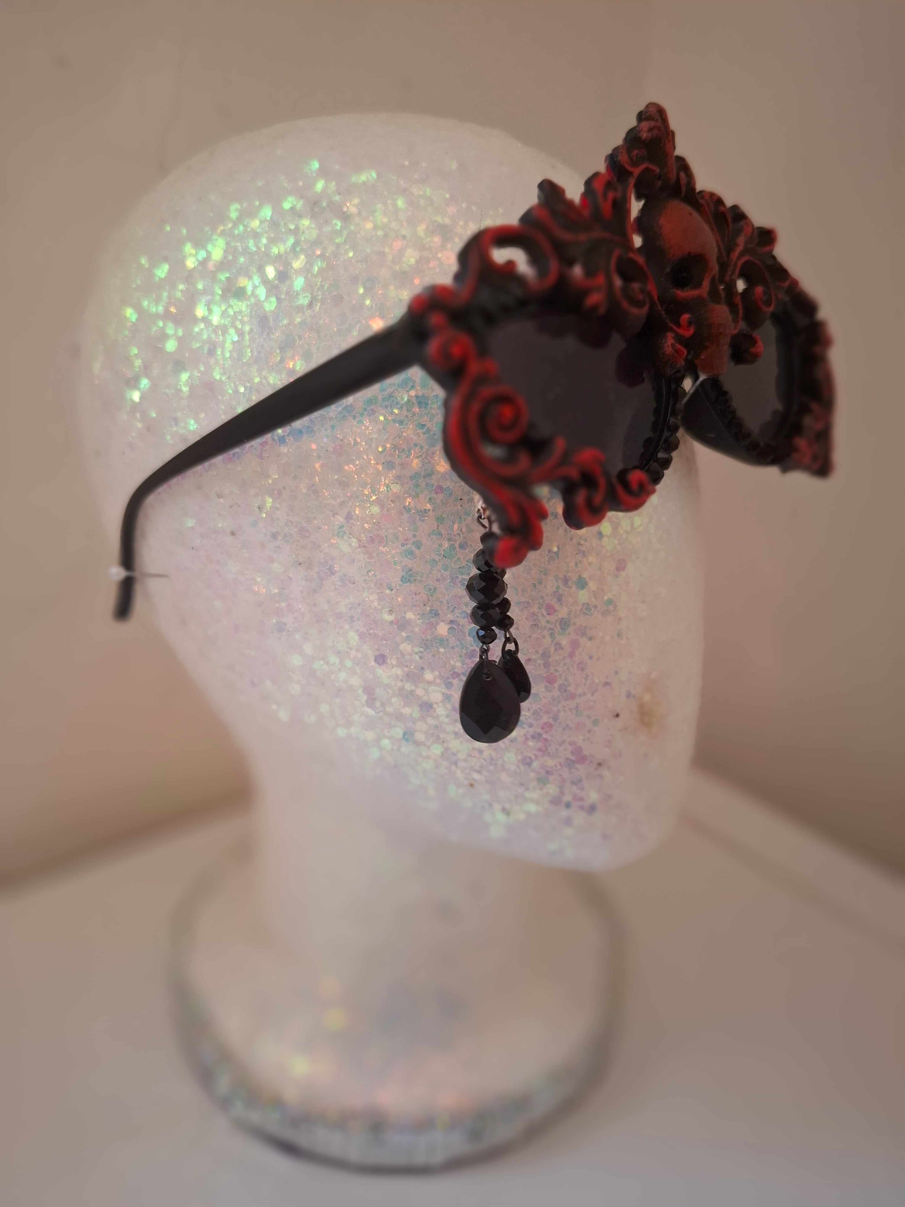 Hand-sculpted sunglasses in deep burgundy scrollwork with a skull centerpiece and black crystals