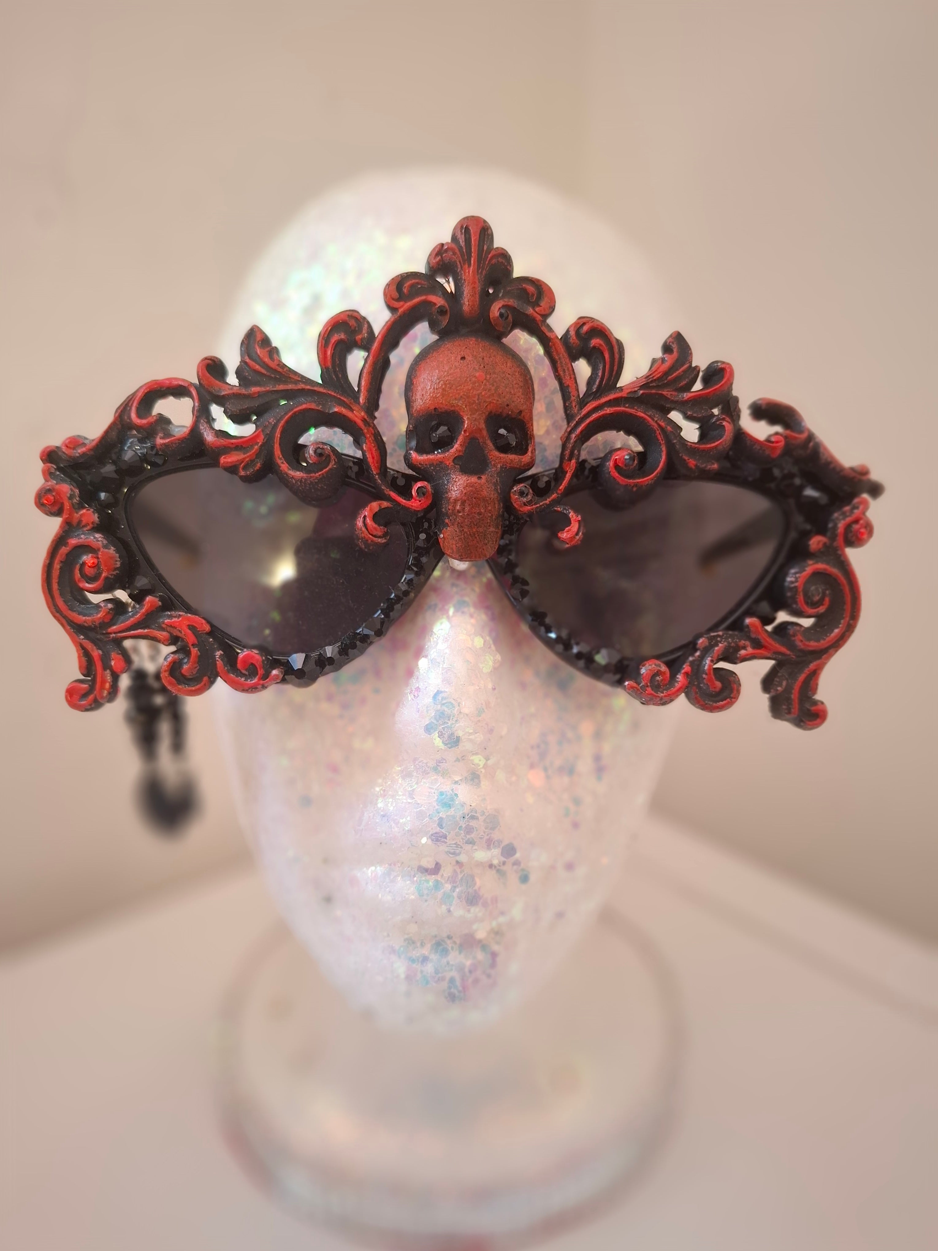 Hand-sculpted sunglasses in deep burgundy scrollwork with a skull centerpiece and black crystals