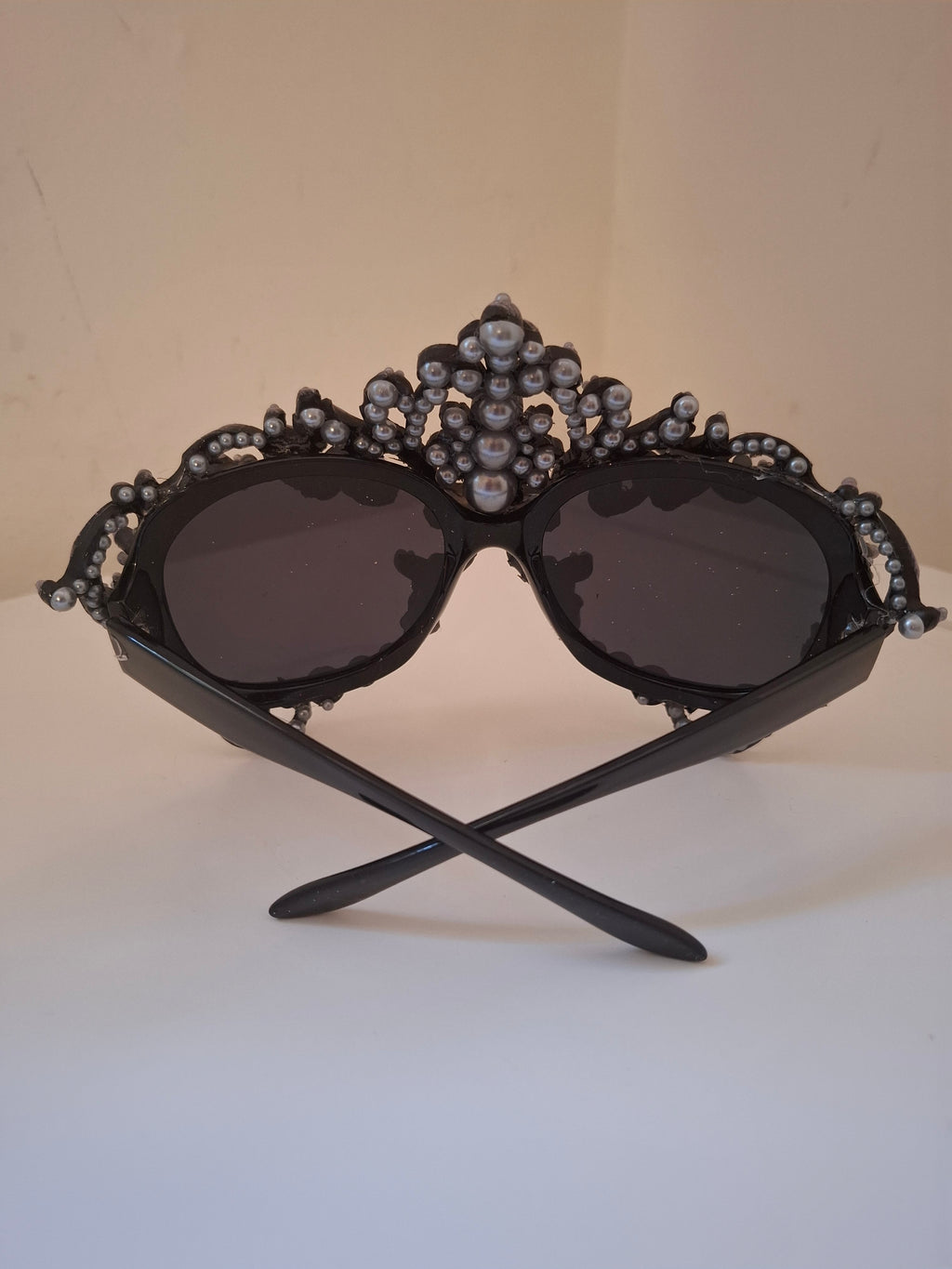  Hand-sculpted sunglasses in deep plum scrollwork with a fleur-de-lis crown and cascading pearl drops. 