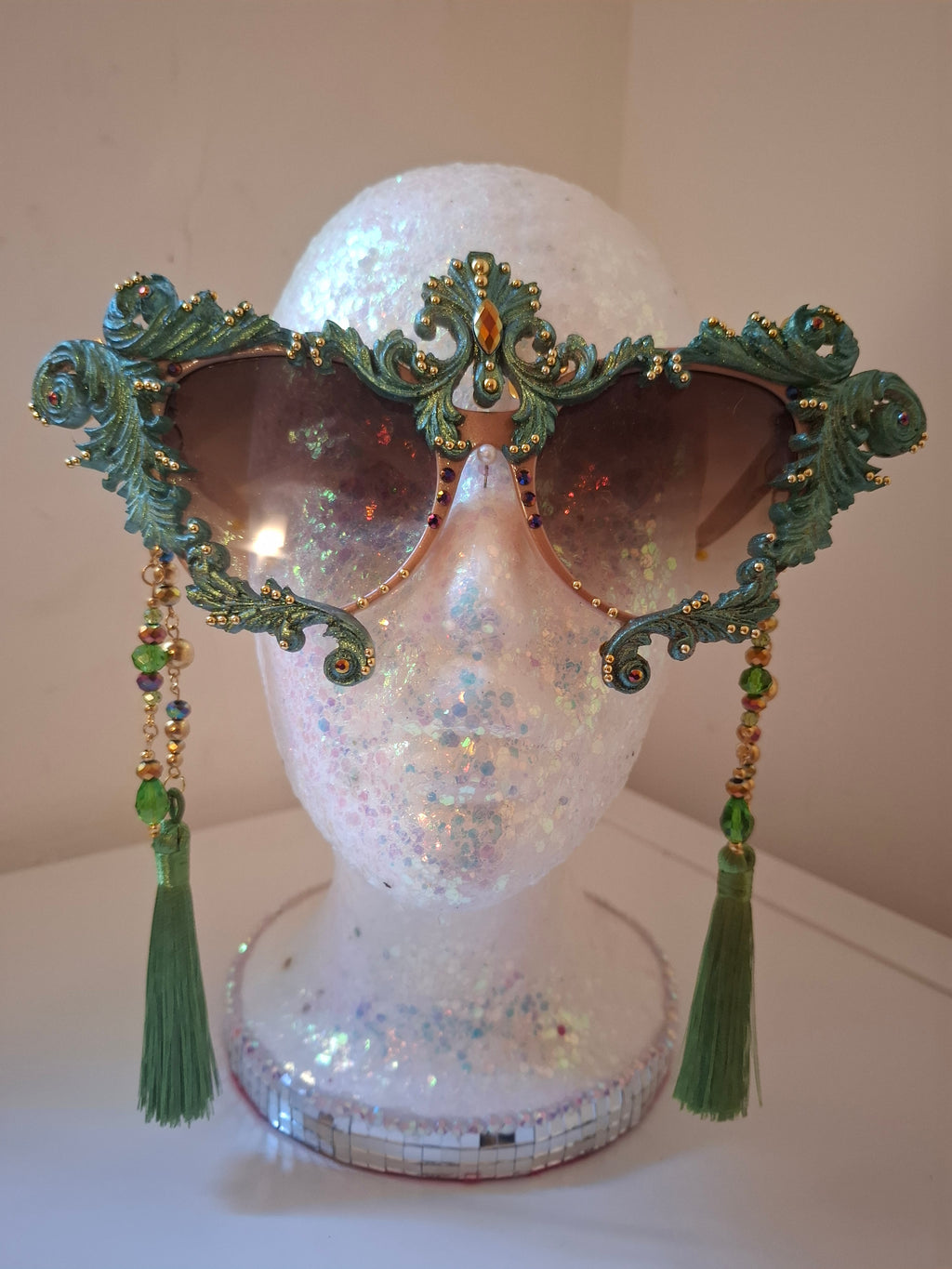 Hand-sculpted sunglasses in copper and forest green verdigris scrollwork with golden accents and emerald tassels.