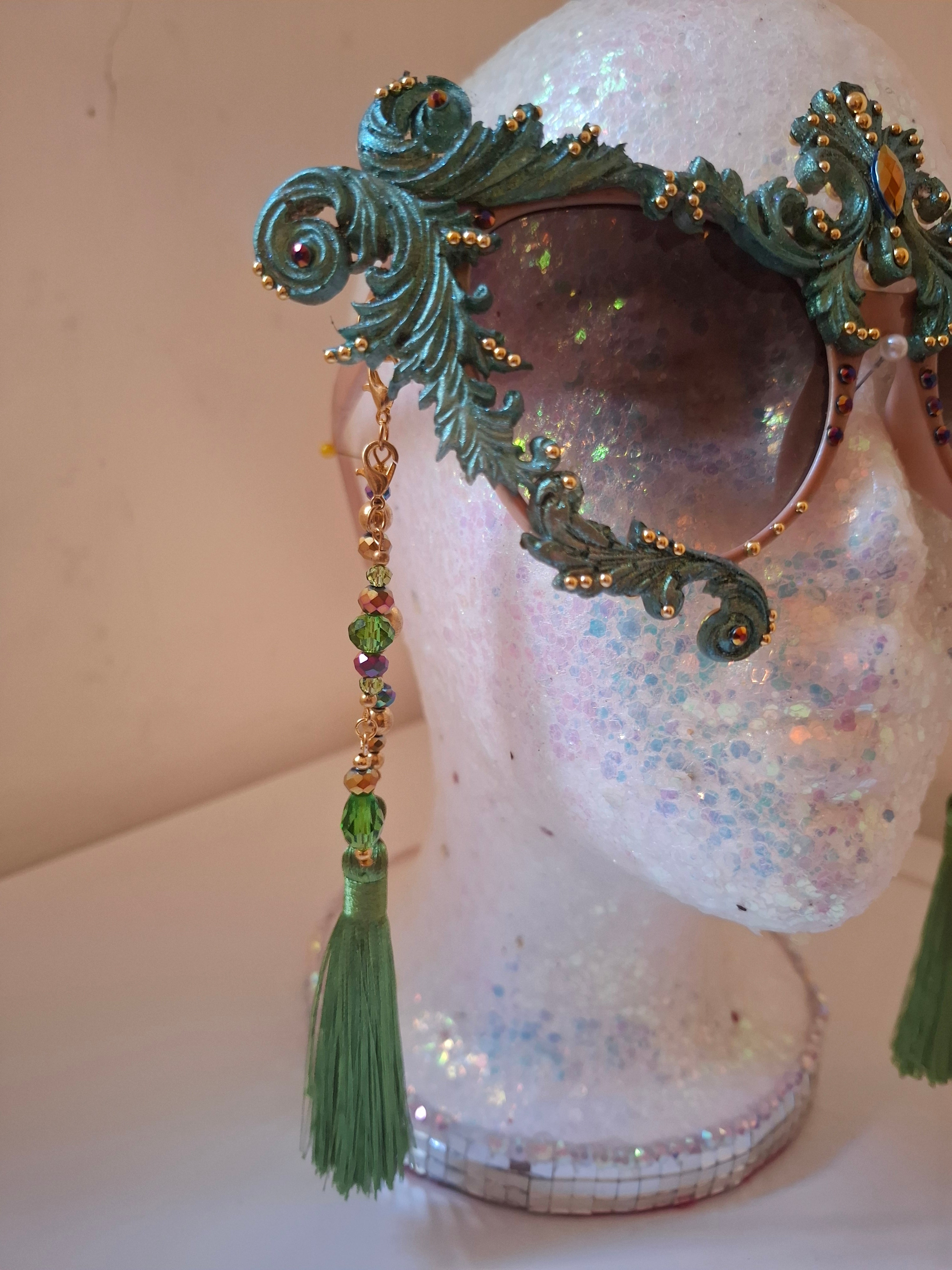 Hand-sculpted sunglasses in copper and forest green verdigris scrollwork with golden accents and emerald tassels.