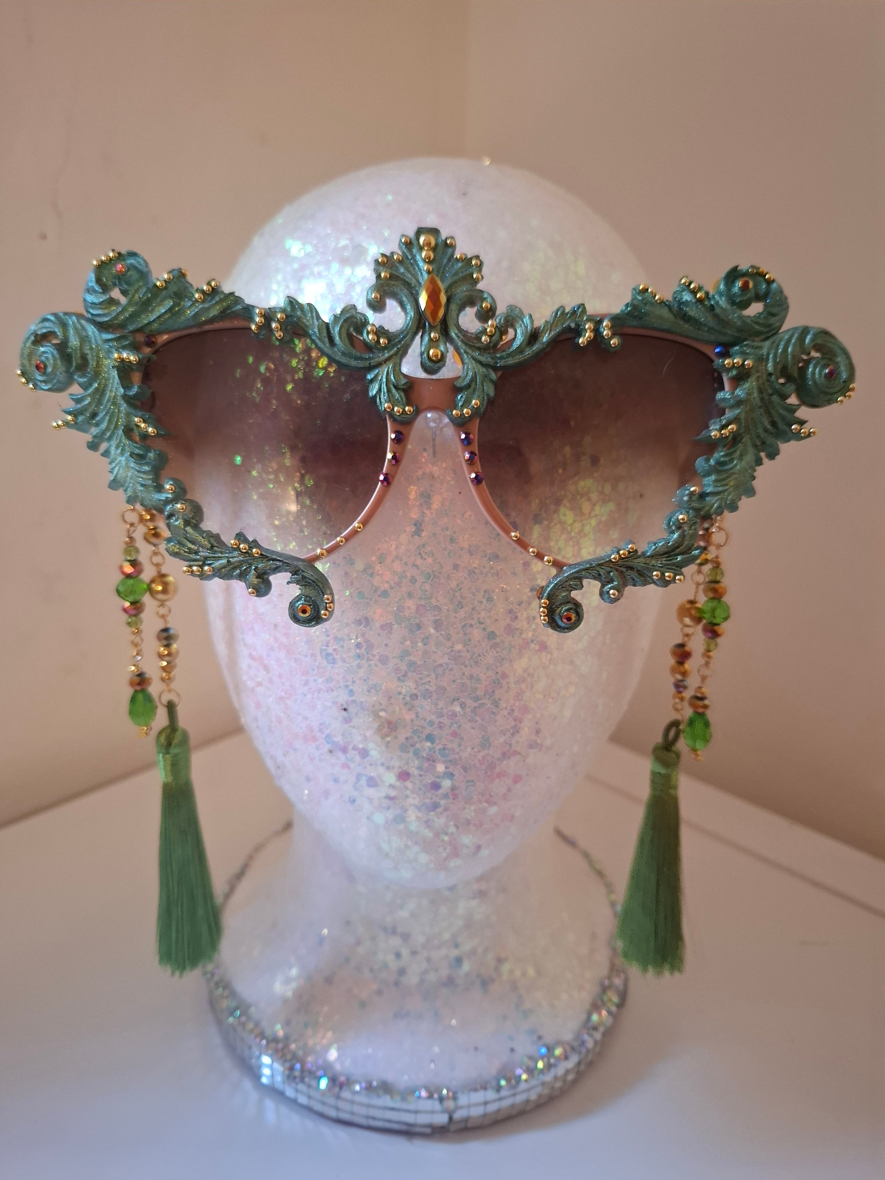 Hand-sculpted sunglasses in copper and forest green verdigris scrollwork with golden accents and emerald tassels.
