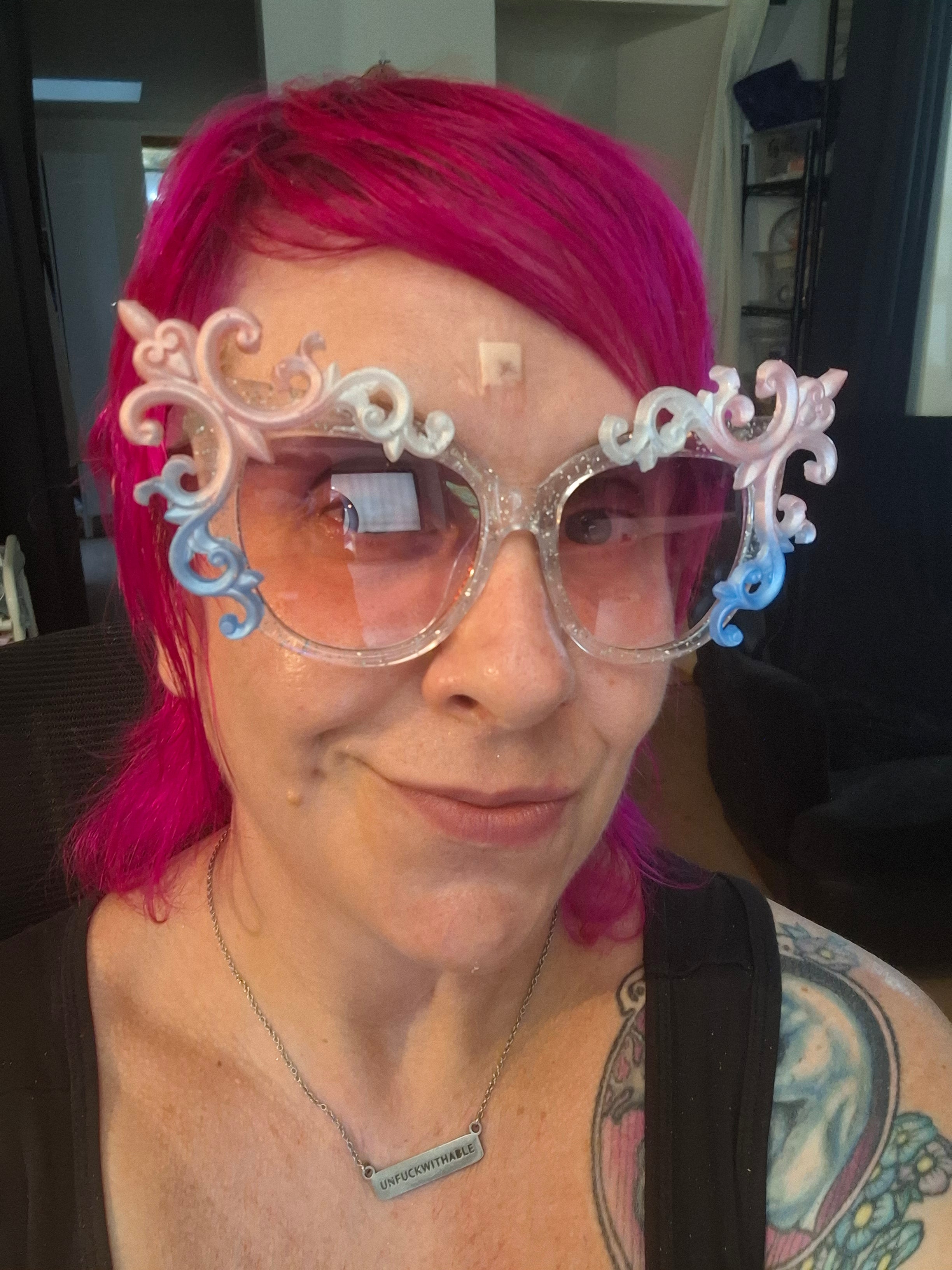Hand-sculpted Pride sunglasses in trans flag colors — pink, white, and blue, with beaded tassels.
