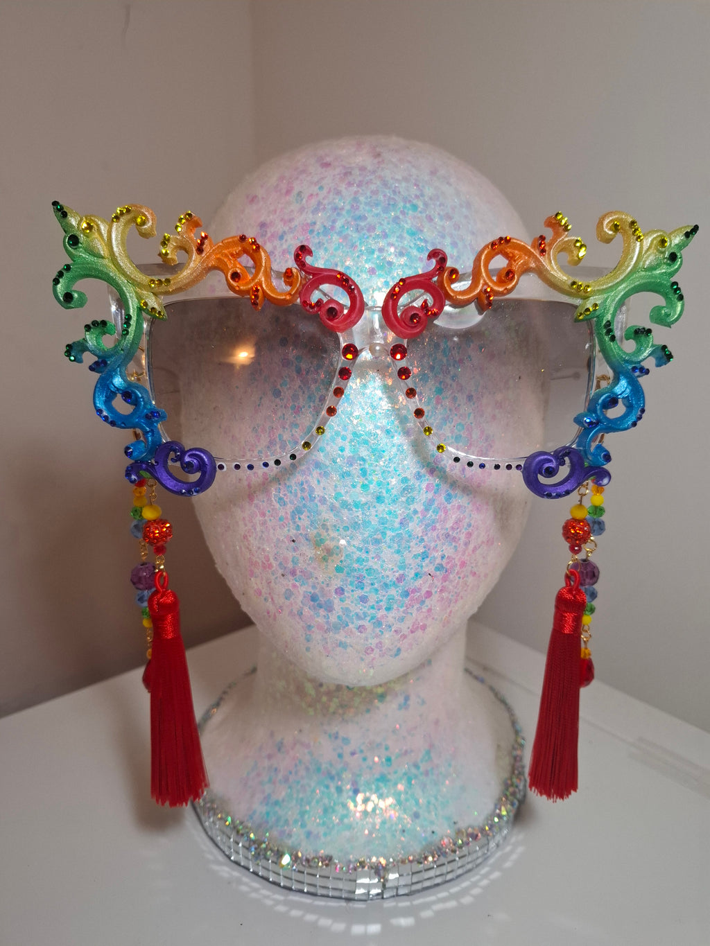 Hand-sculpted Pride sunglasses in classic rainbow flag colors, with red beaded tassels.

