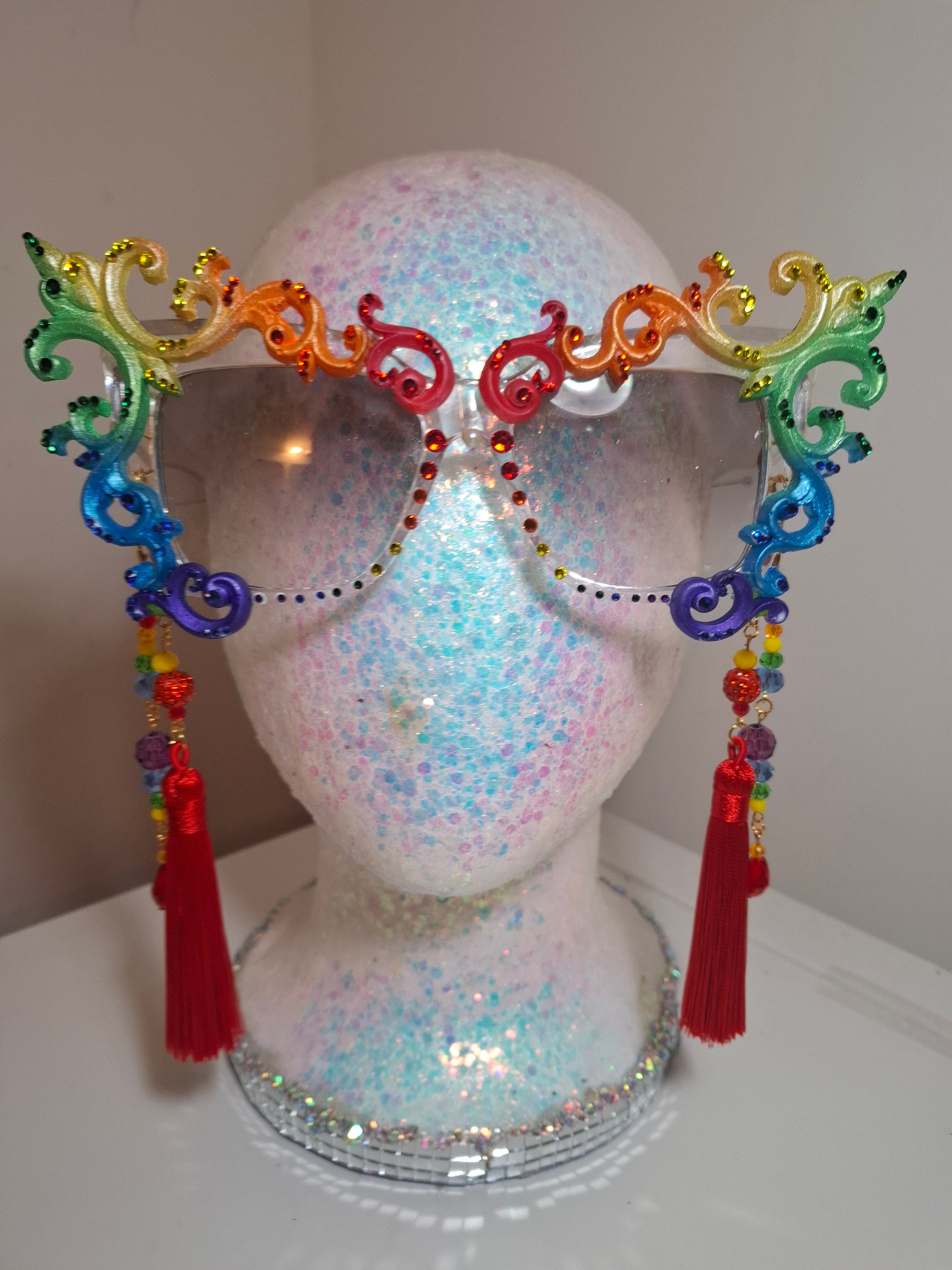 Hand-sculpted Pride sunglasses in classic rainbow flag colors, with red beaded tassels.
