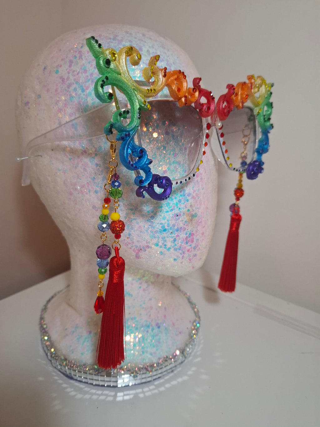 Hand-sculpted Pride sunglasses in classic rainbow flag colors, with red beaded tassels.
