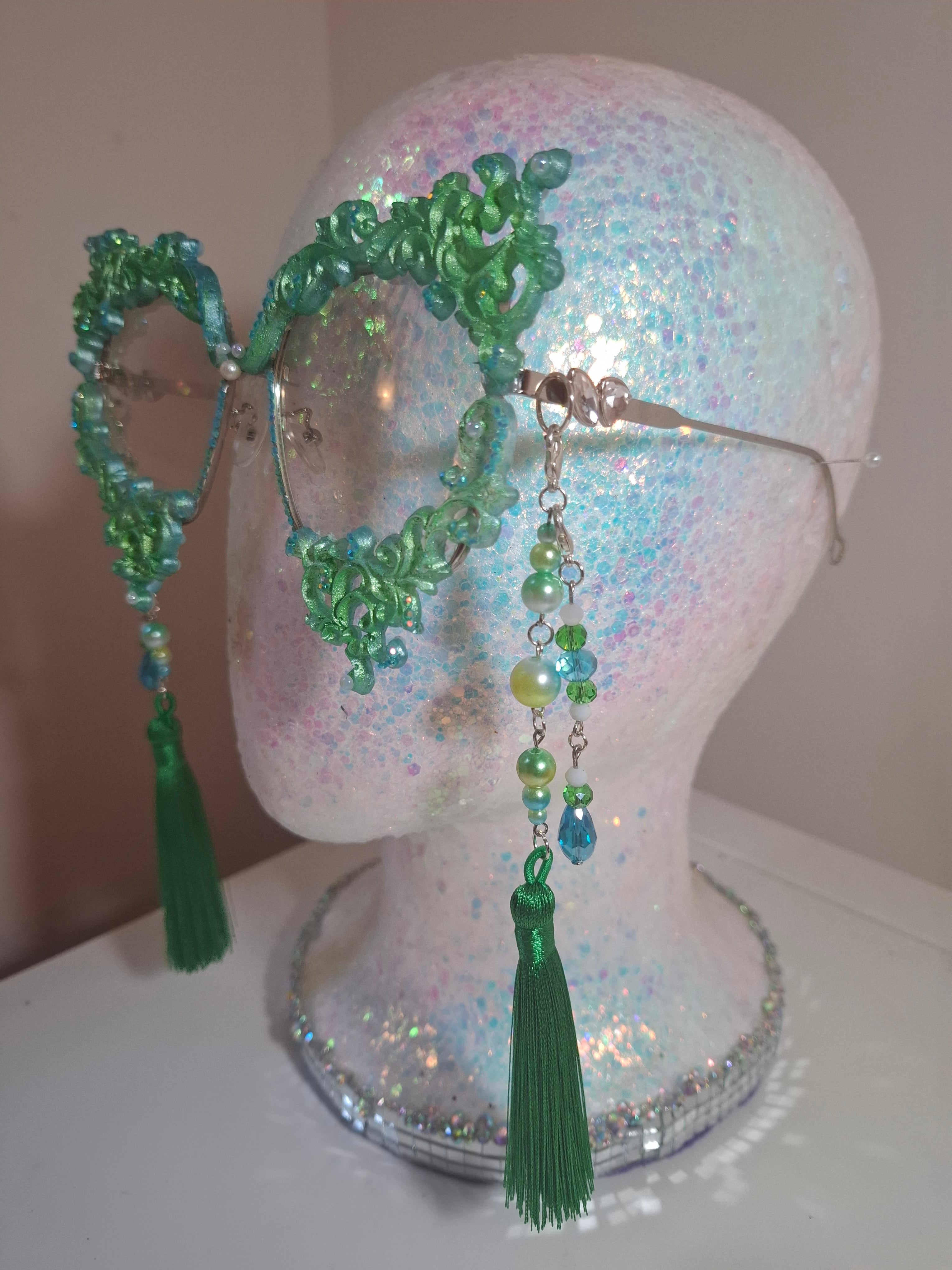 Hand-sculpted sunglasses in soft green scrollwork with pearls and tassels.
