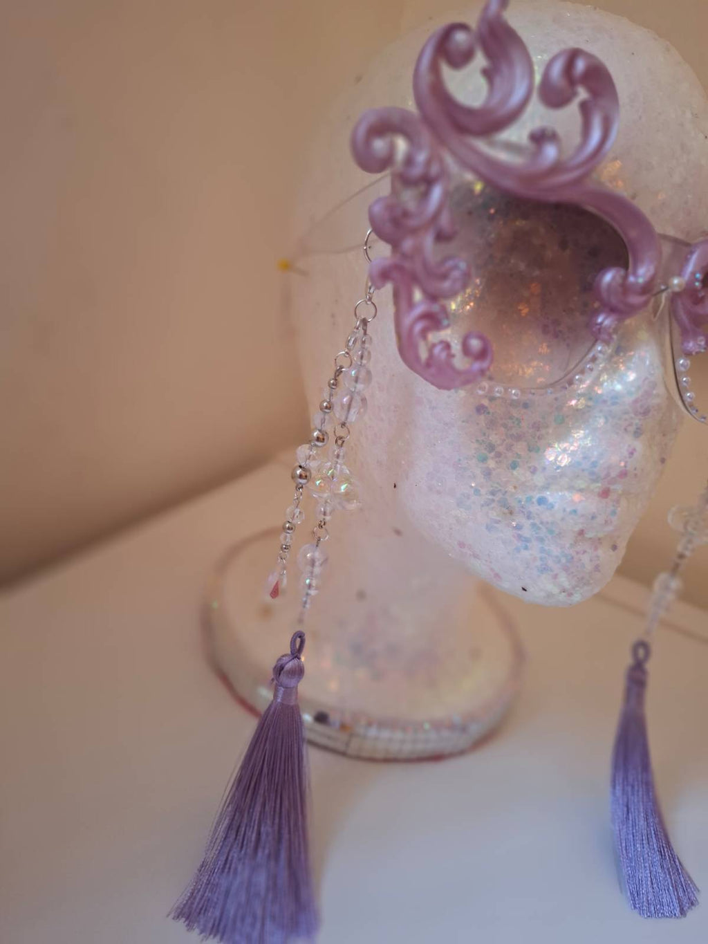 Hand-sculpted sunglasses in soft lavender scrollwork with opalescent pearls and lilac tassels.